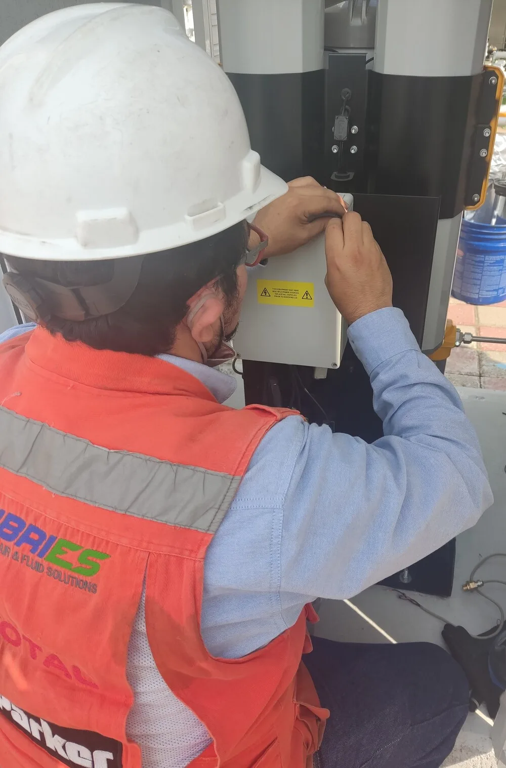 Técnico de Lubries realizando mantenimiento sobre el panel de control de un equipo industrial en planta.